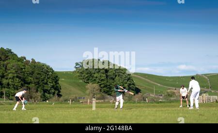 Wensleydale, UK. 04th June, 2021. 4 June 2021 - Hawes, North Yorkshire - Village cricket in what has to be one of the most scenic little grounds as Hawes bat on their home ground at Haylands on the banks of the River Ure. Credit: Wayne HUTCHINSON/Alamy Live News Stock Photo