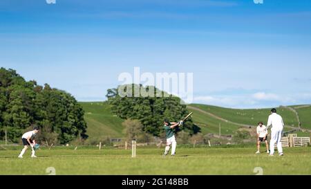 Wensleydale, UK. 04th June, 2021. 4 June 2021 - Hawes, North Yorkshire - Village cricket in what has to be one of the most scenic little grounds as Hawes bat on their home ground at Haylands on the banks of the River Ure. Credit: Wayne HUTCHINSON/Alamy Live News Stock Photo