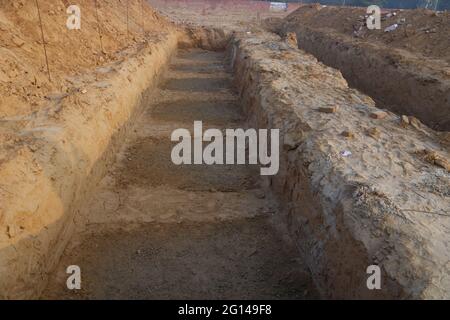 Long deep pit in the ground.  Digging a foundation pit for a building. Stock Photo