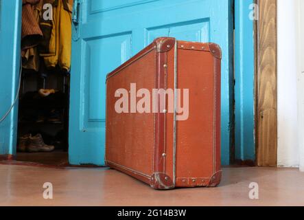 Vintage old brown suitcase in front of an open door Stock Photo