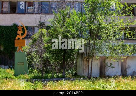 Soviet symbols with sickle and hammer in front of an abandoned Soviet era glass factory near the town of Tokmok, Kyrgyzstan Stock Photo