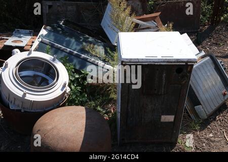 Old broken household appliances in a landfill. Washing machine, gas stove, etc. Stock Photo