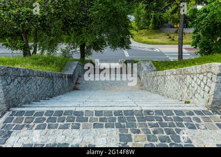 Fence and staircase made of granite stones. A cobbled area with a stone cobblestone fence. Observation deck in the city park Stock Photo