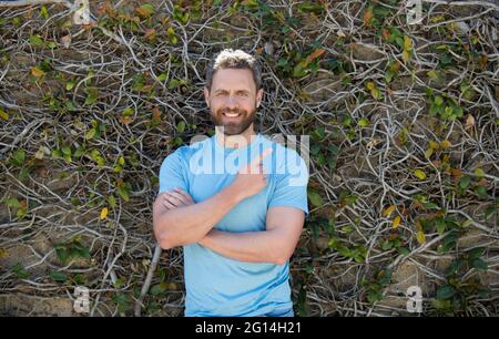 happy bearded mature man in summer shirt pointing finger on natural background, advertisement Stock Photo