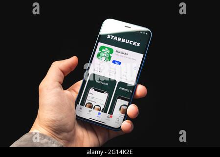 Kharkov, Ukraine - June 4, 2021: Man uses Starbucks app, mpbile phone in hand Stock Photo