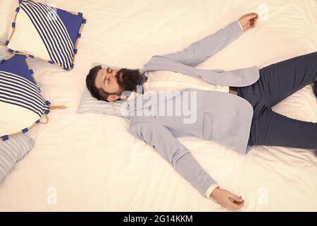 One more long day ended. Feel tired and sleepy. Sleepy guy in formal clothes sleep on bed. Lack of sleep. Need more sleep. Evening time. Businessman Stock Photo