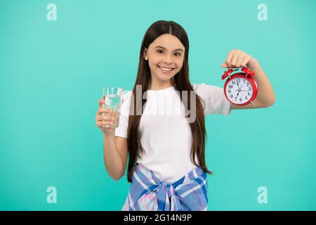 happy kid hold glass of water and clock to stay hydrated and keep daily water balance, thirst. Stock Photo