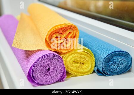 Four rolls multicolored Crepe Paper for creation lie on sill. Stock Photo