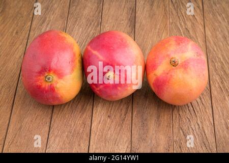 Delicious tommy mango on wooden table - Mangifera indica Stock Photo