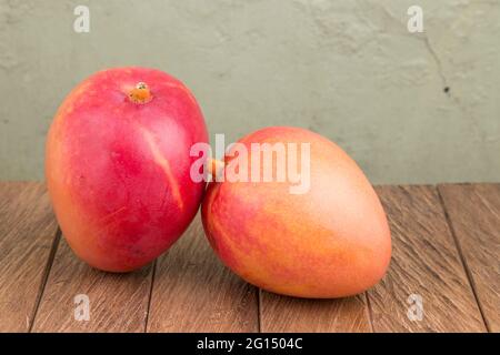 Delicious tommy mango on wooden table - Mangifera indica Stock Photo