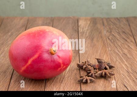 Delicious tommy mango on wooden table - Mangifera indica Stock Photo