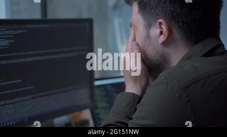 Home office. Handsome man working late at home. Tired young male feels pain, eye strain, dry irritated eyes, fatigue from working at monitor Stock Photo