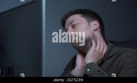 Home office. Handsome man working late at home. Tired young male feels pain, eye strain, dry irritated eyes, fatigue from working at monitor Stock Photo