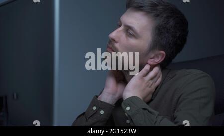Home office. Handsome man working late at home. Tired young male feels pain, eye strain, dry irritated eyes, fatigue from working at monitor Stock Photo