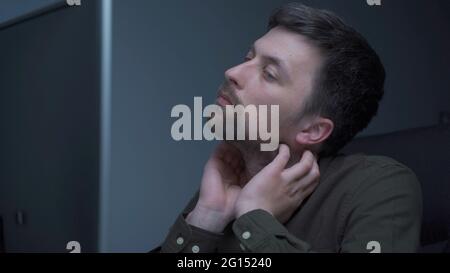 Tired male working on computer. Sad exhausted man at home office. Stressful work, stress at workplace. Software developer looks very tired during Stock Photo