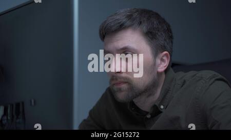 Home office. Handsome man working late at home. Tired young male feels pain, eye strain, dry irritated eyes, fatigue from working at monitor Stock Photo