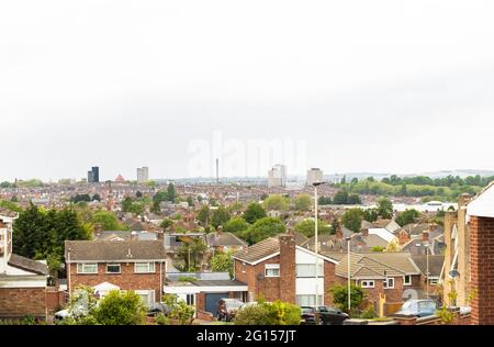 Looking over tops of houses and Leicester city centre skyline, tower blocks, St. George’s Tower, Charnwood Forest in the hills.