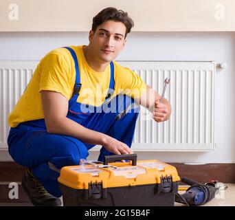 The young repairman contractor repairing heating panel Stock Photo