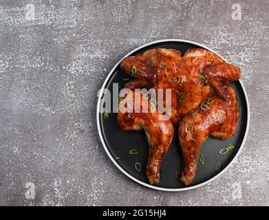 Roasted whole chicken on a round plate on a dark background. Top view, flat lay Stock Photo