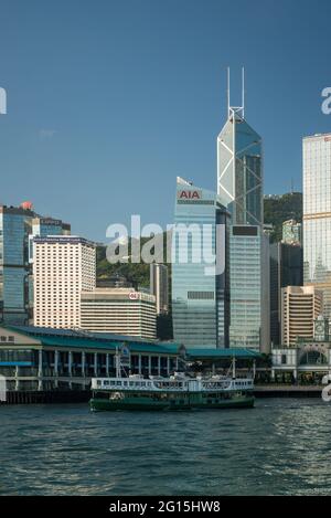 An iconic Star Ferry leaves Central Pier 7 to cross  Victoria Harbour in front of the Bank of China Building, Central, Hong Kong Island Stock Photo