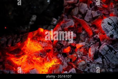 Burning log of wood close-up as abstract background. The hot embers of burning wood log fire. Firewood burning on grill. Texture fire bonfire embers. Stock Photo