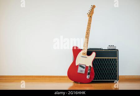 Red electric guitar on white wall background, copy space Stock Photo