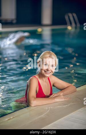 Cute blonde woman in red swimming suit spending time in a pool Stock Photo