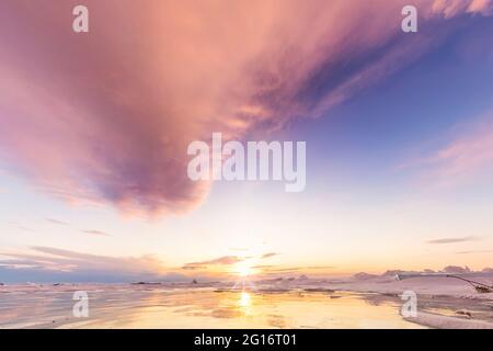 landscape pink clouds at dawn on cape khoboy olkhon island lake Baikal in winter on ice with cracked and large white bubbles. Stock Photo