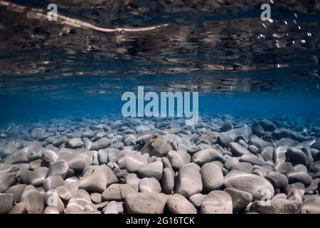 Underwater ocean with stones bottom, reflection and blue water. Stock Photo