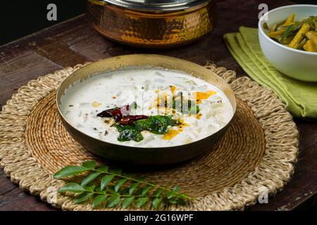 Pachadi or Raitha and olan Kerala feast side dishes ,vegeterian food  items arranged in a brass vessel  and white bowl which is placed on wooden backg Stock Photo