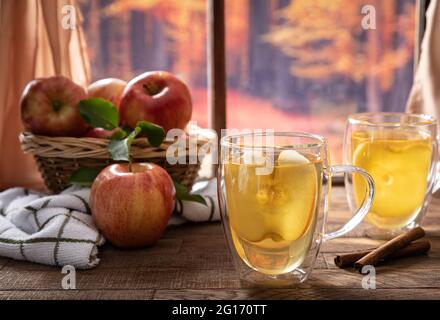 Glass of apple juice and fresh apples by a window with autumn background scene Stock Photo