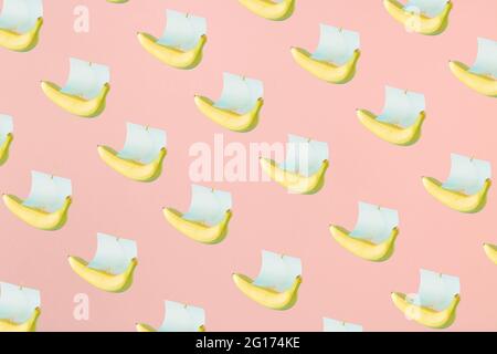 A yellow banana and a paper sail like a ship on a pastel pink background. Travel Abstract 3D Ad Background Art. Stock Photo