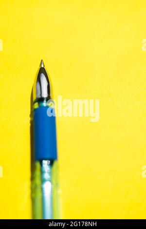 Blue ball pen closeup on a bright sunny yellow paper. Stock Photo