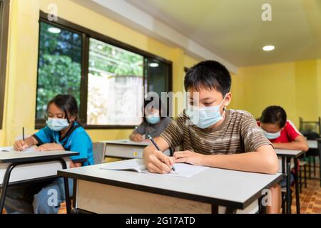 Group of asian children studying in classroom with face mask back at school after covid-19 quarantine and lockdown. Stock Photo