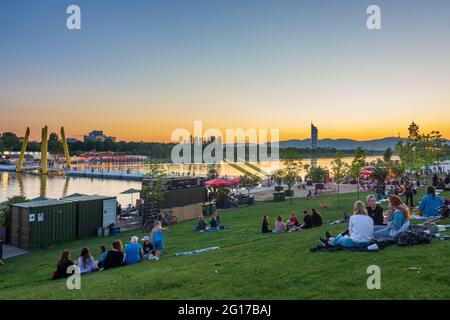 Wien, Vienna: sunset at Copa Beach, river Neue Donau (New Danube), people on meadow, view to Wienerwald in 22. Donaustadt, Wien, Austria Stock Photo