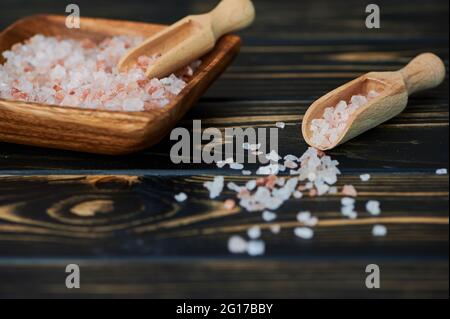 pink Himalayan salt in a small wooden scoop beside a bowl Stock Photo