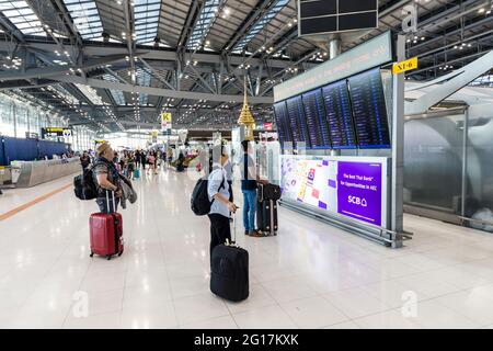 Travellers watching the departures board at Suvarnabhumi Airport, Bangkok, Thailand Stock Photo