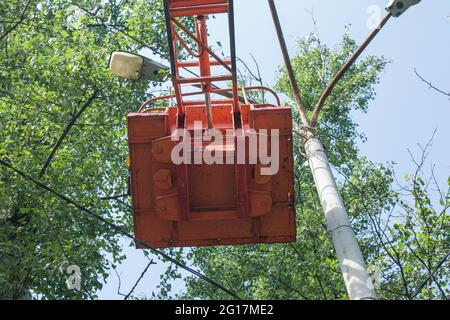 A municipal worker in protective equipment performs hazardous work to eliminate an interruption in the power grid. A worker repairs a street lamp from Stock Photo