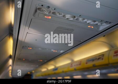 Air conditioning or ventilation knobs and reading light lamps above passenger seats in airplane, closeup detail Stock Photo