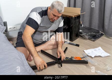 man assembles a chair according to instructions Stock Photo