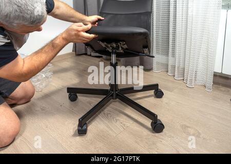 a man assembles a new chair at home. Stock Photo