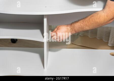 master assembles a new shelf at home Stock Photo