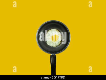 Warm omelette placed on black teflon on a yellow background. Stock Photo