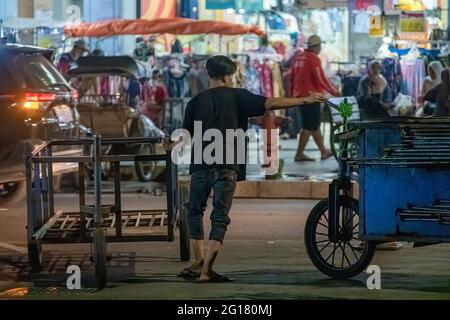 Yogyakarta, indonesia,  january 2021 :  a man trying to hold a food cart crossing on a busy street Stock Photo