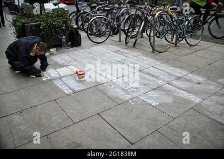 DUBLIN, IRELAND-- MAY 28, 2012: Homeless man writing a sad message on the floor, begging for small change, near to Grafton Street . Stock Photo