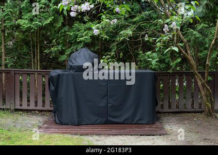Barbeque grill Cover protecting kamado-style ceramic grill from rain. Outdoor cooking equipment. Stock Photo