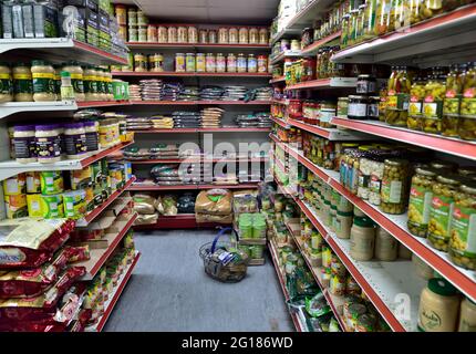 Shelves full of bags of dried pulses, lentils and other with jars and tins of food in small local well stocked corner grocery shop, UK Stock Photo