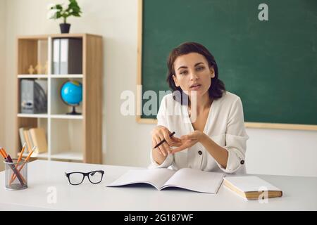 Smiling young school teacher looking at webcam giving remote class lesson Stock Photo