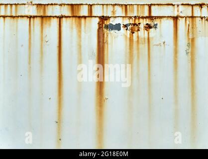 Orange rust streaks down a white wall Stock Photo