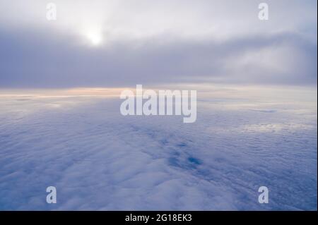 View from the window of a passenger plane during the flight. Clouds from above. Stock Photo